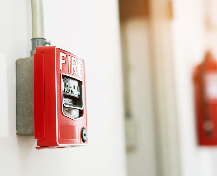 Manual pull fire alarm switch safety system box installed and fire extinguisher on white wall background